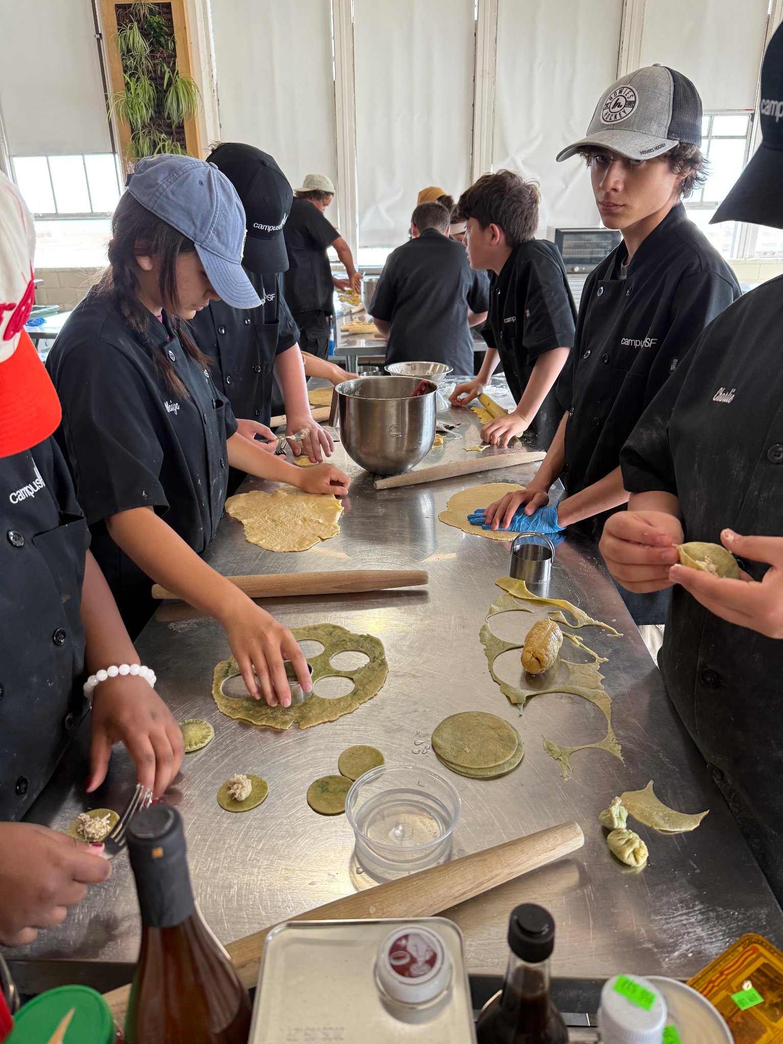 Campers rolling and shaping dough at a wide kitchen workstation